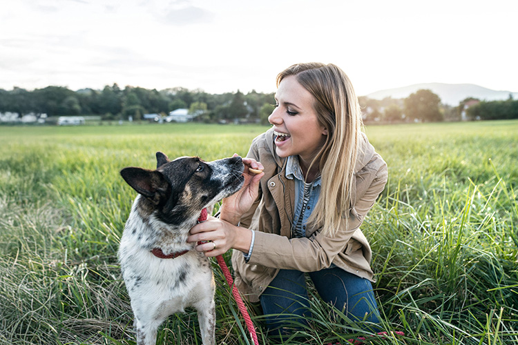 A woman and her dog in a green field of grass