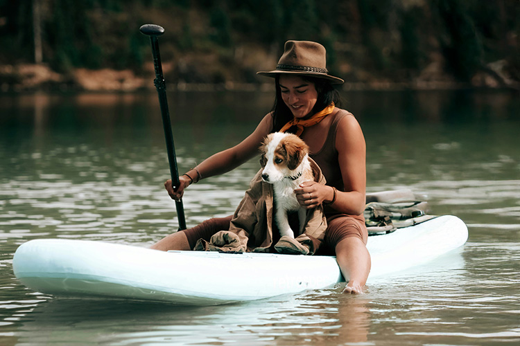 A woman and puppy on a paddle board